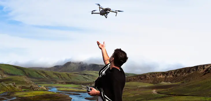 Man in a valley in front of a river letting Raptor 8K Drone loose